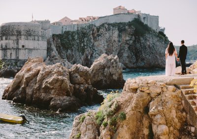 ein paar steht auf einer klippe und schaut auf´s meer